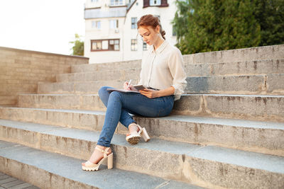 Full length of woman sitting on staircase