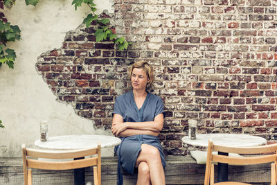 Portrait of woman sitting on chair against wall