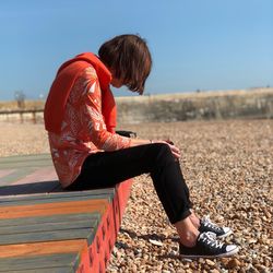 Full length of woman sitting against clear sky