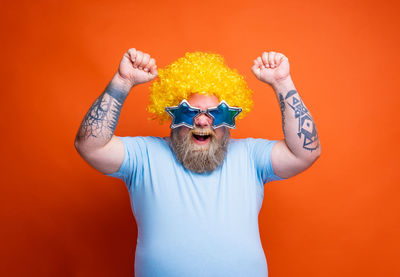 Rear view of woman with arms raised against yellow background