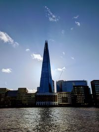 Buildings by river against sky in city