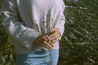 Midsection of woman holding plant standing outdoors