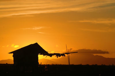 Silhouette built structure against dramatic sky during sunset