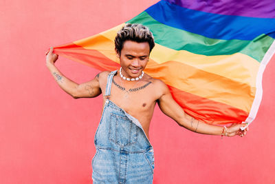 Gay man with rainbow flag against pink background