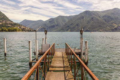 Wooden pier over lake against mountains