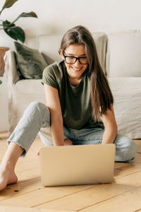 Portrait of young woman sitting on sofa at home