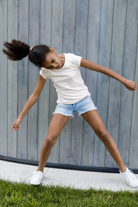 Girl dancing while standing against fence
