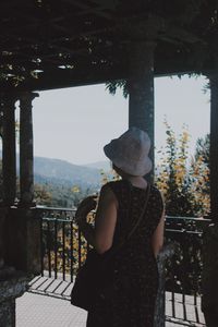 Rear view of woman wearing hat standing in old built structure