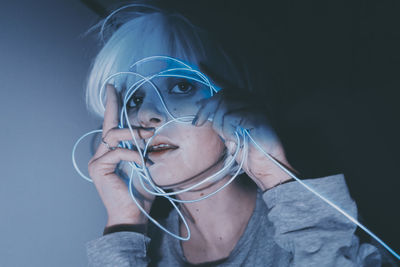 Portrait of young woman wearing mask against black background