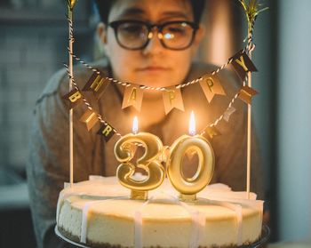 Close-up of woman looking at burning 30 number candle on birthday