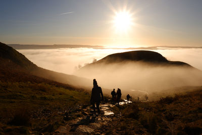 People on mountains against sky during sunset