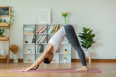 Midsection of woman with arms raised on floor at home