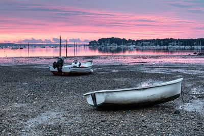 Boats moored on sea against sky during sunset