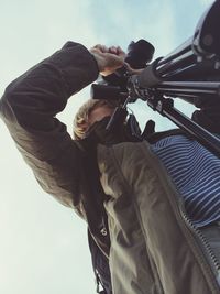 Low angle view of man holding umbrella against sky