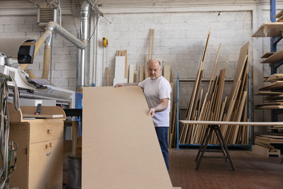 Man operating wood cutting machine while standing at factory