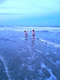 People in sea against blue sky