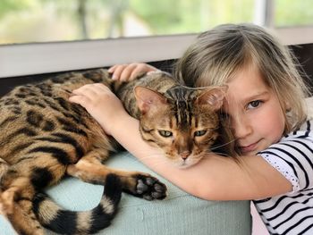 Close-up of cat looking away and a little girl hugging 