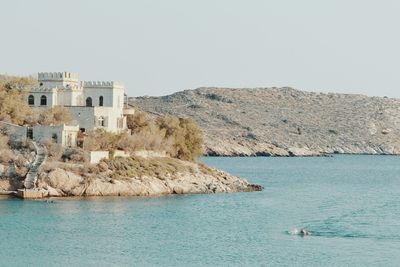 Buildings by sea against clear sky