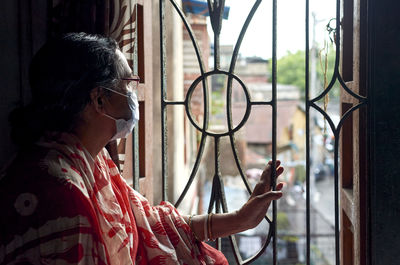 Side view of woman looking through window