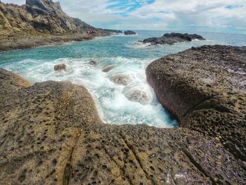 Scenic view of rocks on beach against sky