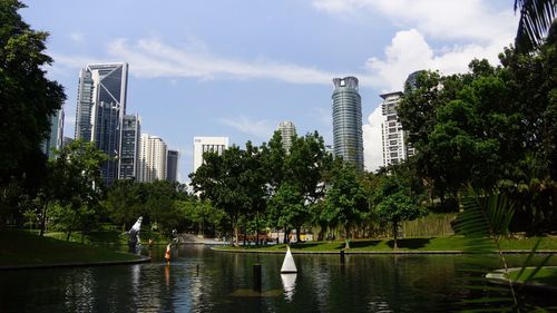 Lake and trees in park against sky in city