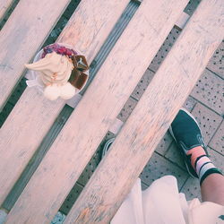 Low section of person standing by wooden bench with ice cream