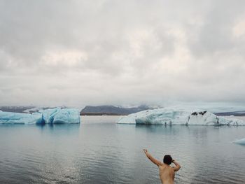 Rear view of woman standing by lake