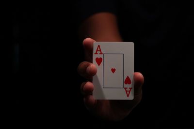 Close-up of hand holding cards over black background