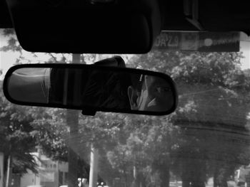 Rear view of man photographing car on side-view mirror