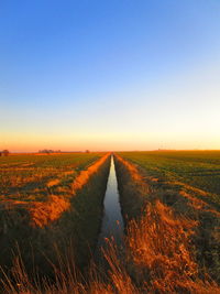 Scenic view of land against clear sky during sunset