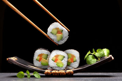 Sushi on plate against black background