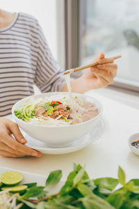 Midsection of woman having food at table