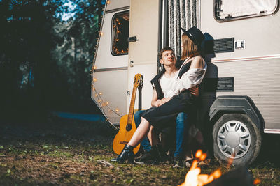 Full length of couple sitting against motor home