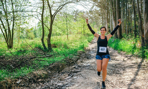 Cheerful woman exercising in forest