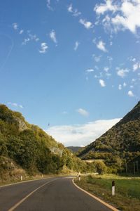 Road by mountains against sky