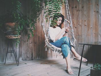 Full length of young woman sitting on hammock