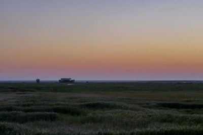 Scenic view of grassy landscape against sky during sunset