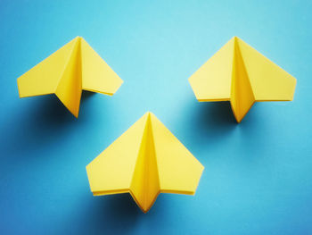 Group of three yellow paper jets on blue background.