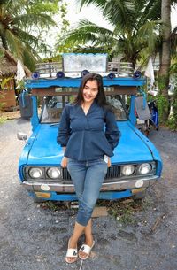 Portrait of smiling young woman standing on car