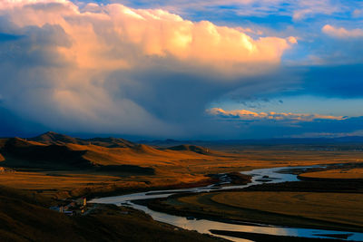 Scenic view of riverbank against cloud sky during sunset