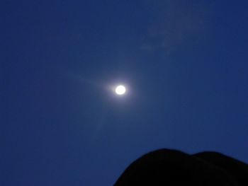 Low angle view of silhouette moon against blue sky