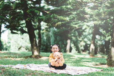 Little asian girl hugging her teddy bear in a park