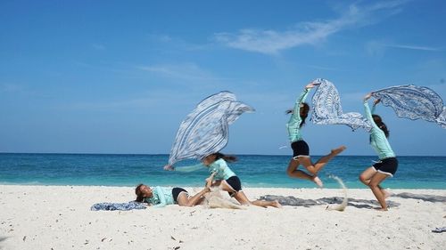 People playing on beach against blue sky