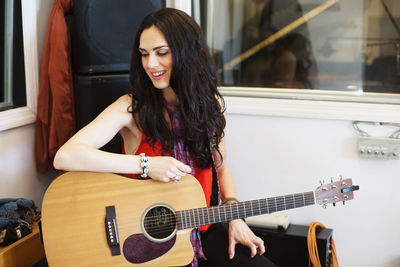 Young woman holding acoustic guitar at a recording studio