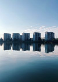 Reflection of buildings in lake against sky in city