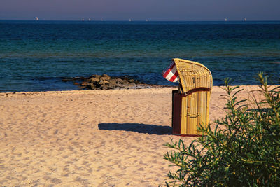Hooded beach chair on shore against sea