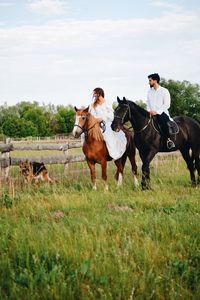 Couple riding horse on field