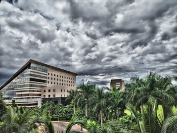 Plants and buildings against cloudy sky