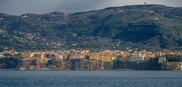 Aerial view of townscape by sea against sky