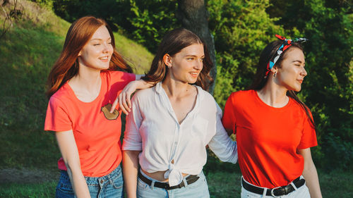 Smiling friends standing against trees